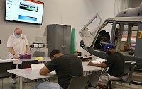 EMCC Workforce Trainer Carey Butler, at left, works with students in the Manufacturing Skills, Composite and Assembly course tailored to provide the skills needed by employees with Aurora Flight Sciences, a Boeing Company.